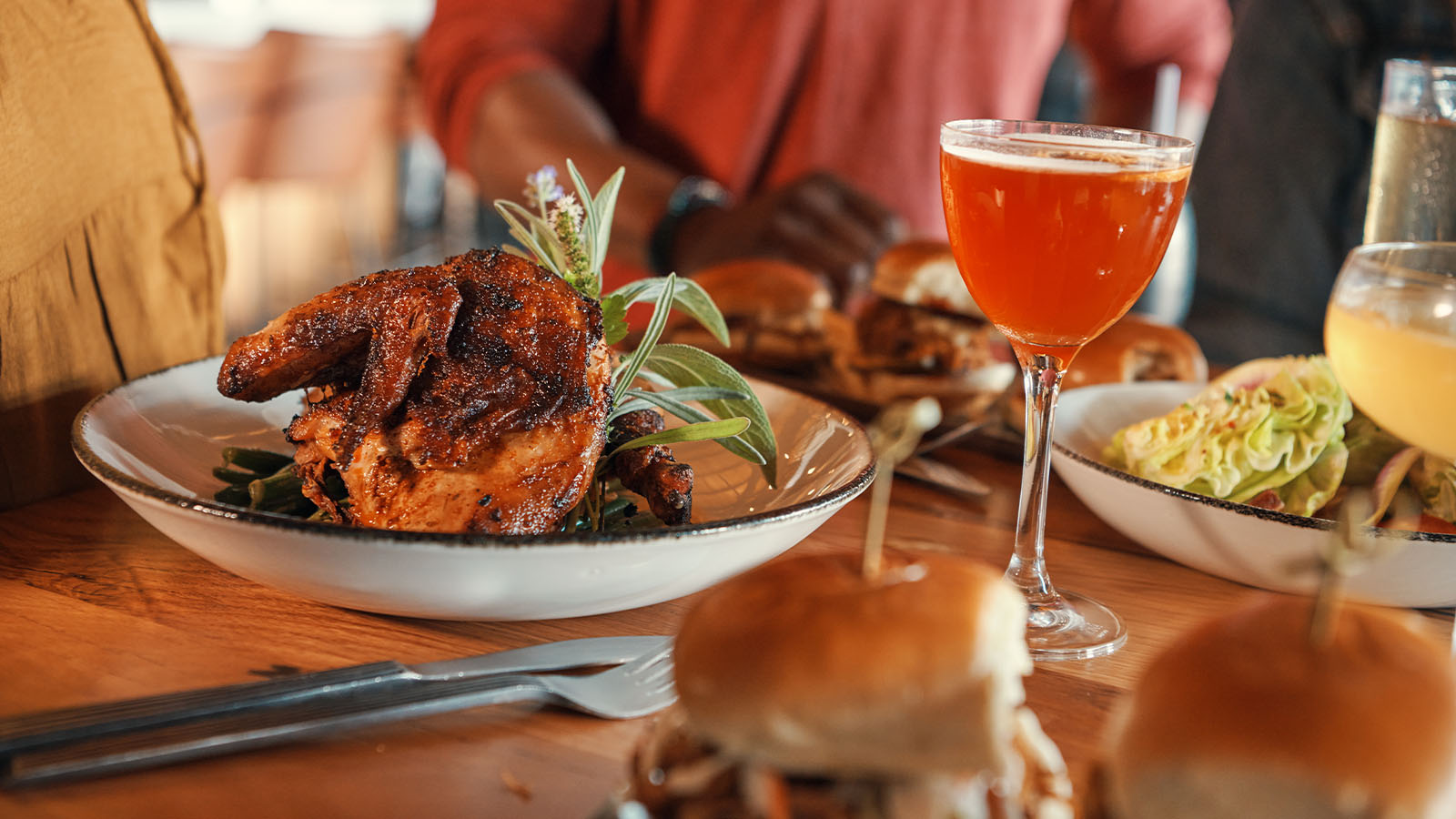 Plated roasted chicken and a bourbon cocktail at The Kitchen Table Restaurant.