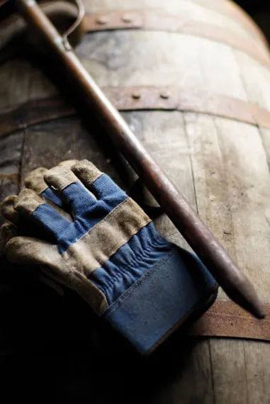 Close-up of gloves and copper bourbon thief on barrel at James B. Beam Distilling Co.