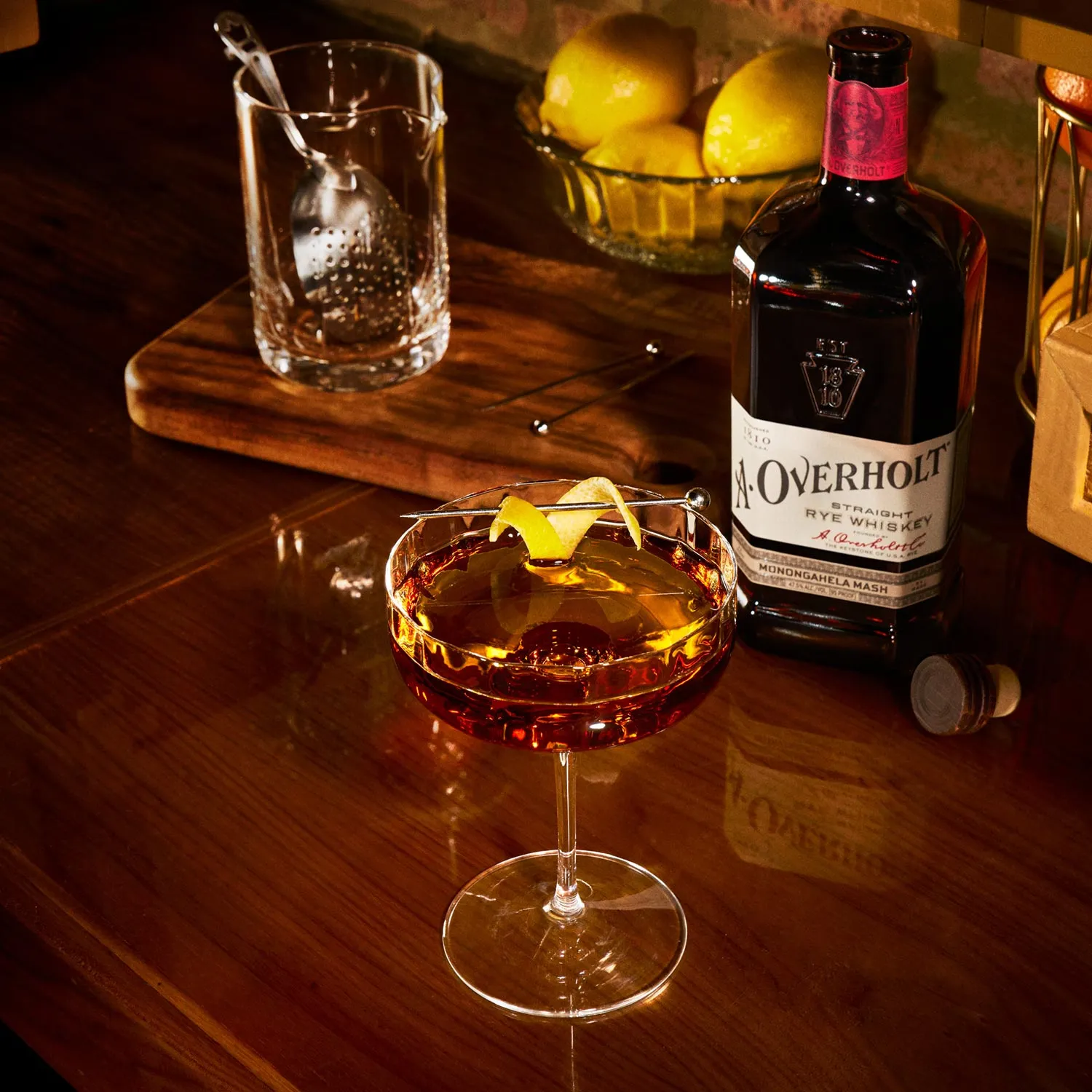 Perfect Manhattan cocktail with a lemon twist, next to Monongahela Mash Straight Rye American Whisky Old Overholt.
