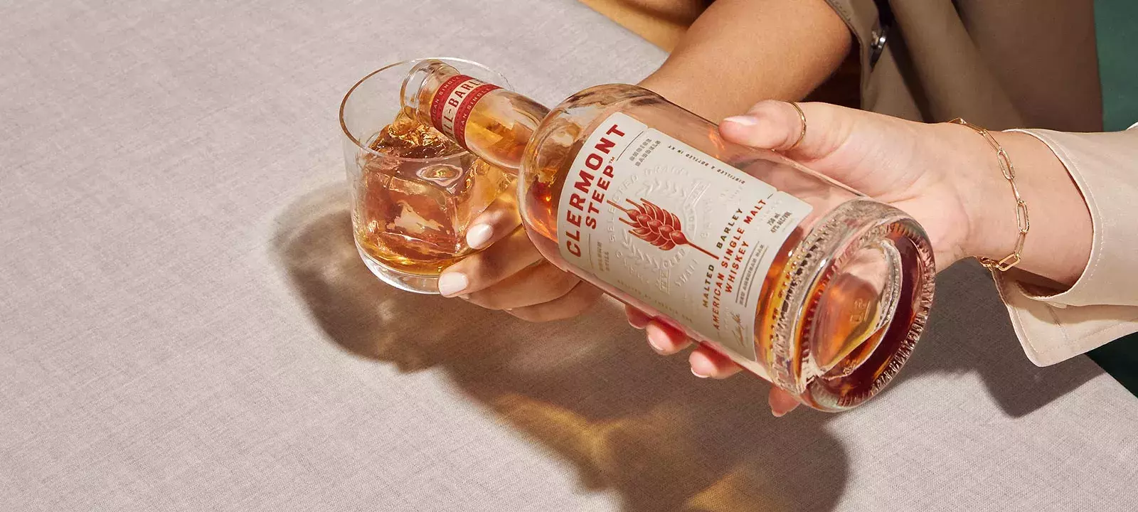 Serving drink on a glass from a bottle of Whisky Clermont Steep