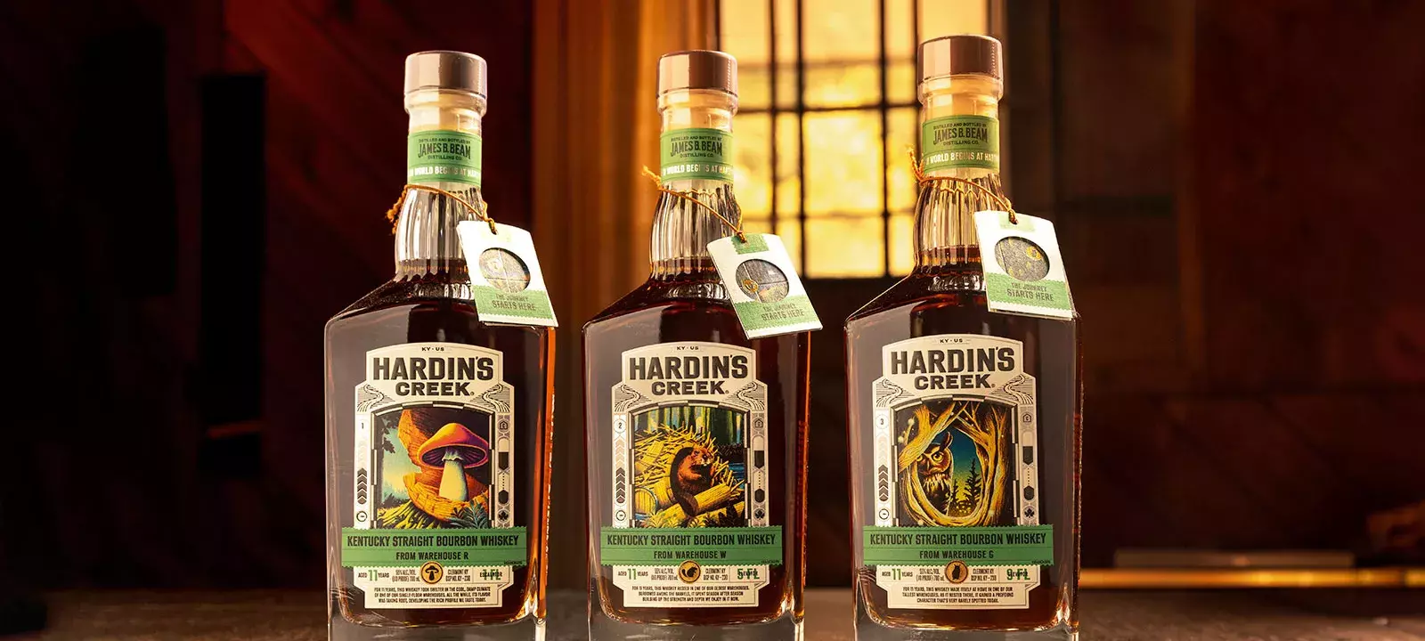 A close-up of a woman wearing a mustard-colored blouse and a gold bracelet, holding a patterned whiskey glass with her hand resting on a dark wooden table Whisky Hardin's Creek