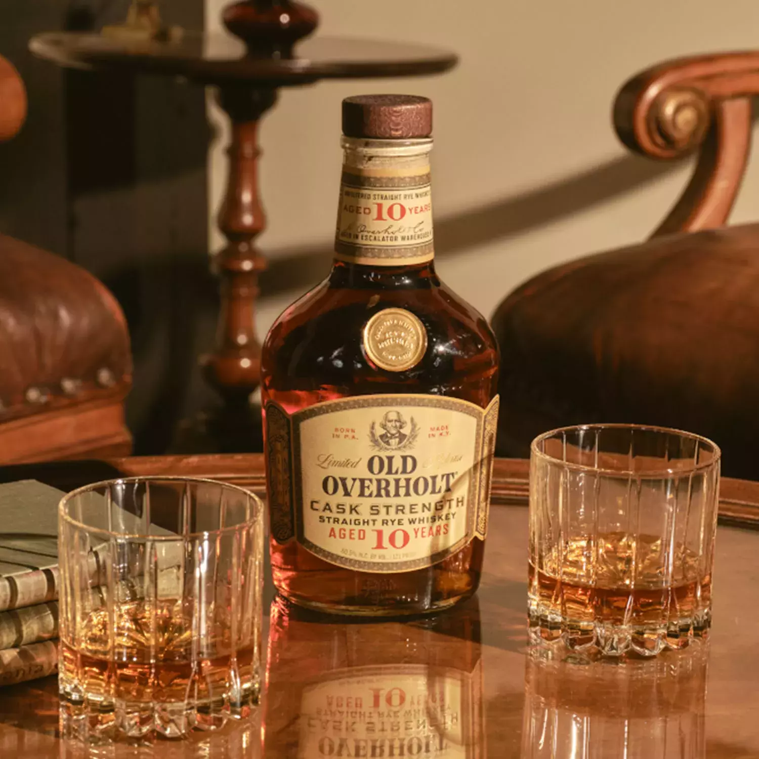 A glass of whiskey with ice next to a bottle of Monongahela Mash Straight Rye American Whisky Old Overholt.
