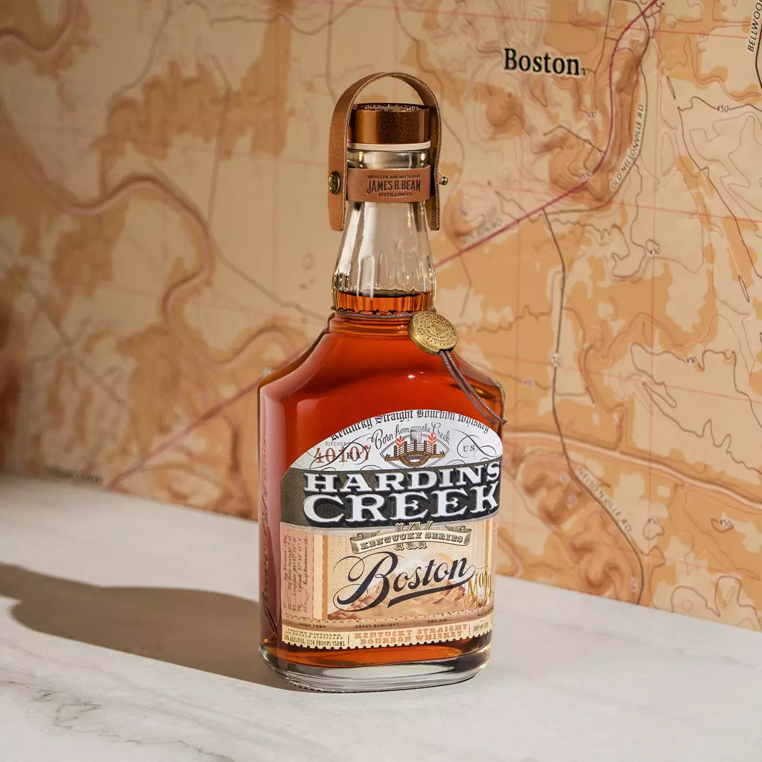 A bottle from the Kentucky Series labeled Boston, positioned in front of a tan and white topographical map featuring the city's name Whisky Hardin's Creek