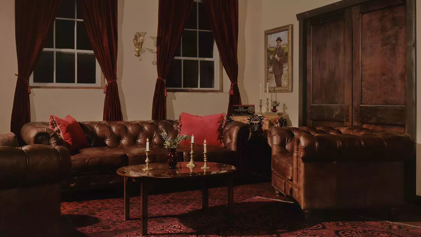 A dimly lit, luxurious room with brown tufted leather sofas and armchairs, home to American Whisky Old Overholt