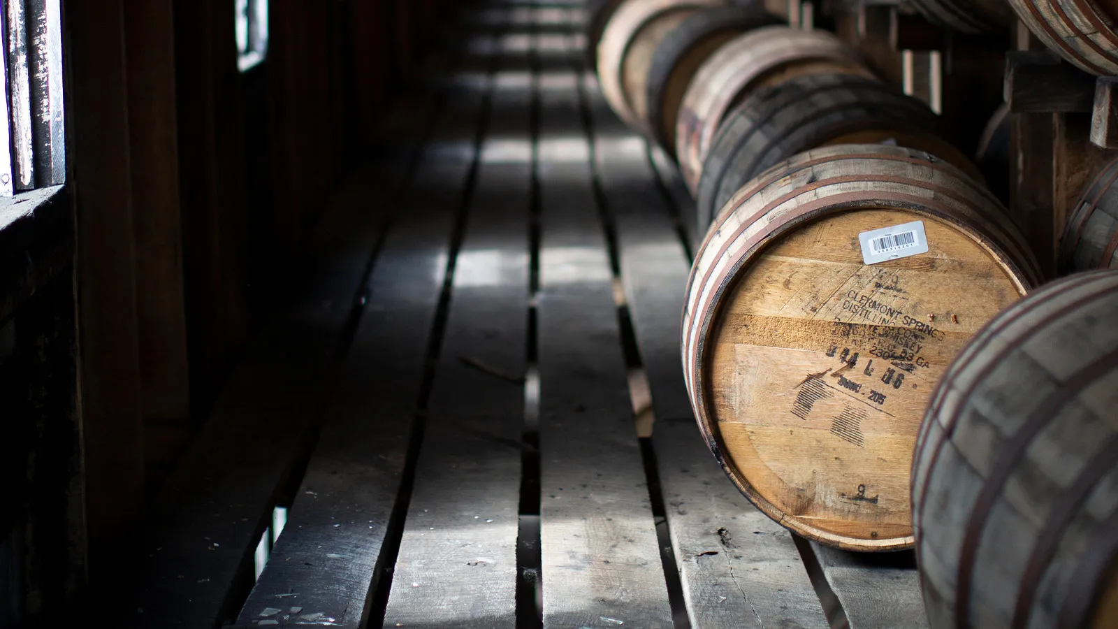 Oak barrels aging in a long, dark corridor of a James B. Beam Distilling Co. bourbon rackhouse.