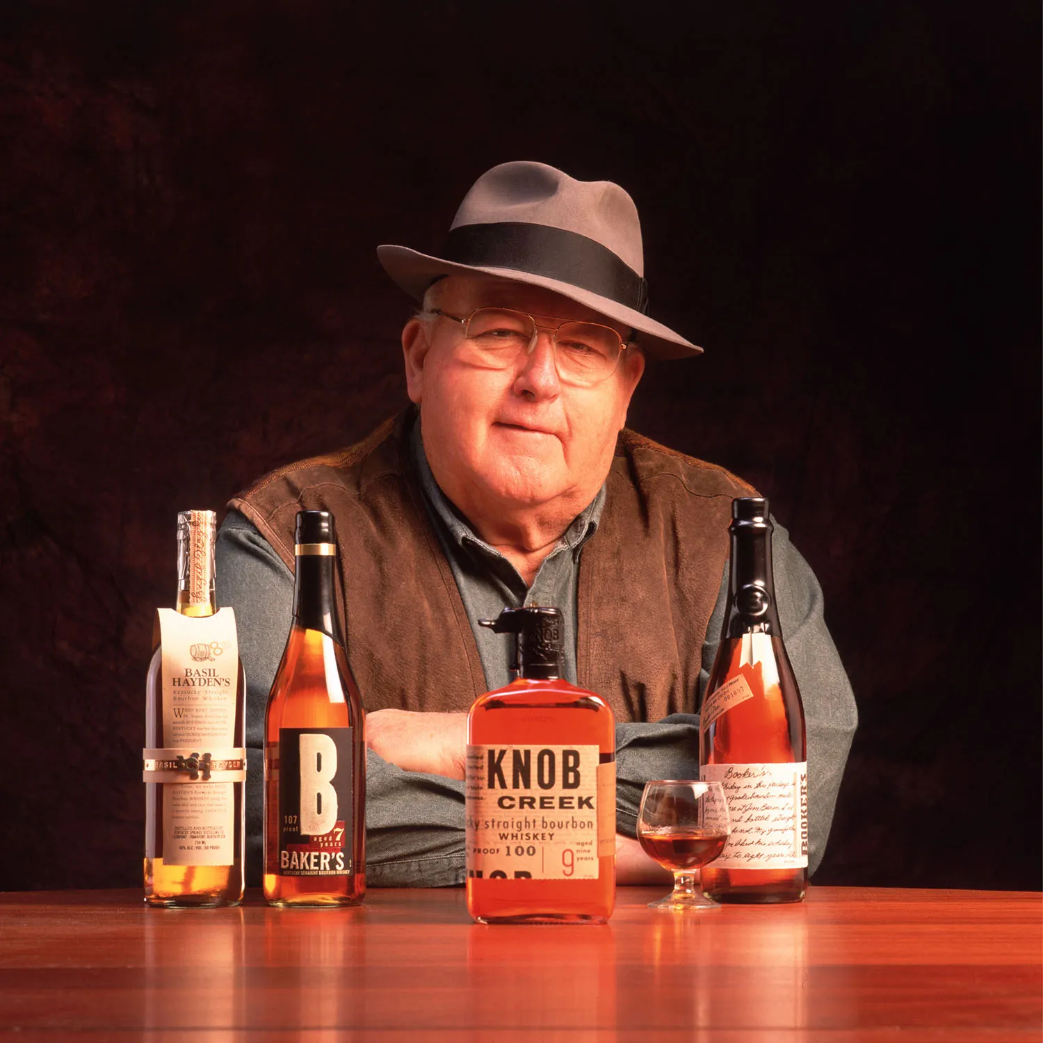 6th generation master distiller Booker Noe posing with is small batch collection; Basil Hayden, Baker's, Knob Creek, and Booker's.