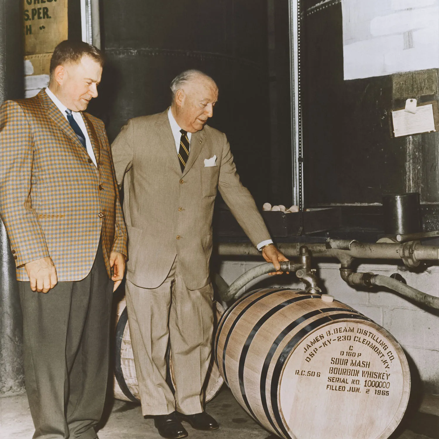Colorized photo of  T. Jeremiah Beam and a distiller filling the millionth bourbon barrel. James B. Beam Distilling Co. history.