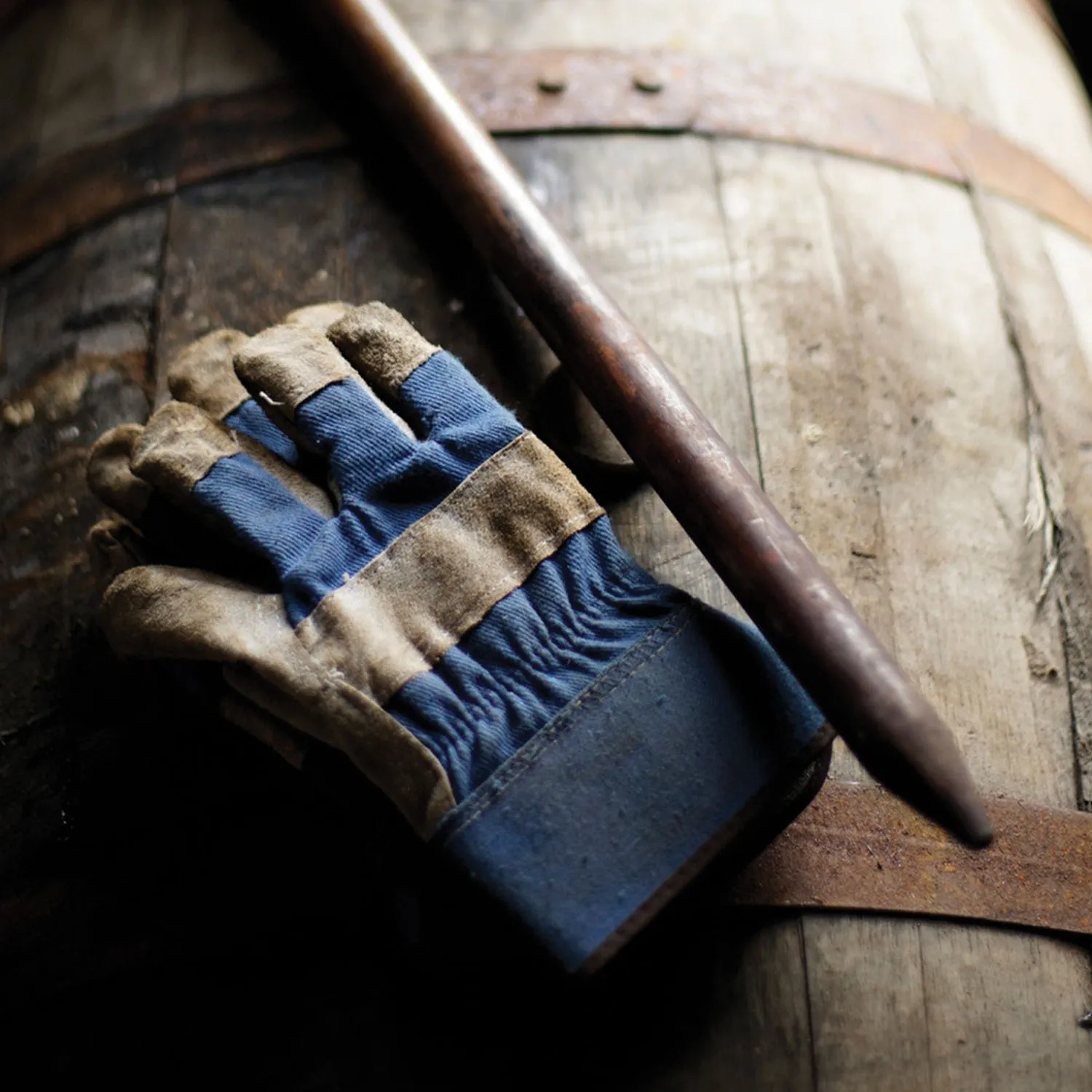 Bourbon thief and work gloves rest on an aging barrel in a James B. Beam Distilling Co. rackhouse.