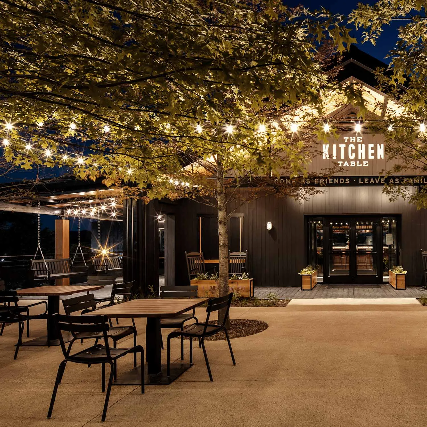 Exterior of The Kitchen Table restaurant at night, with string lights illuminating the courtyard.