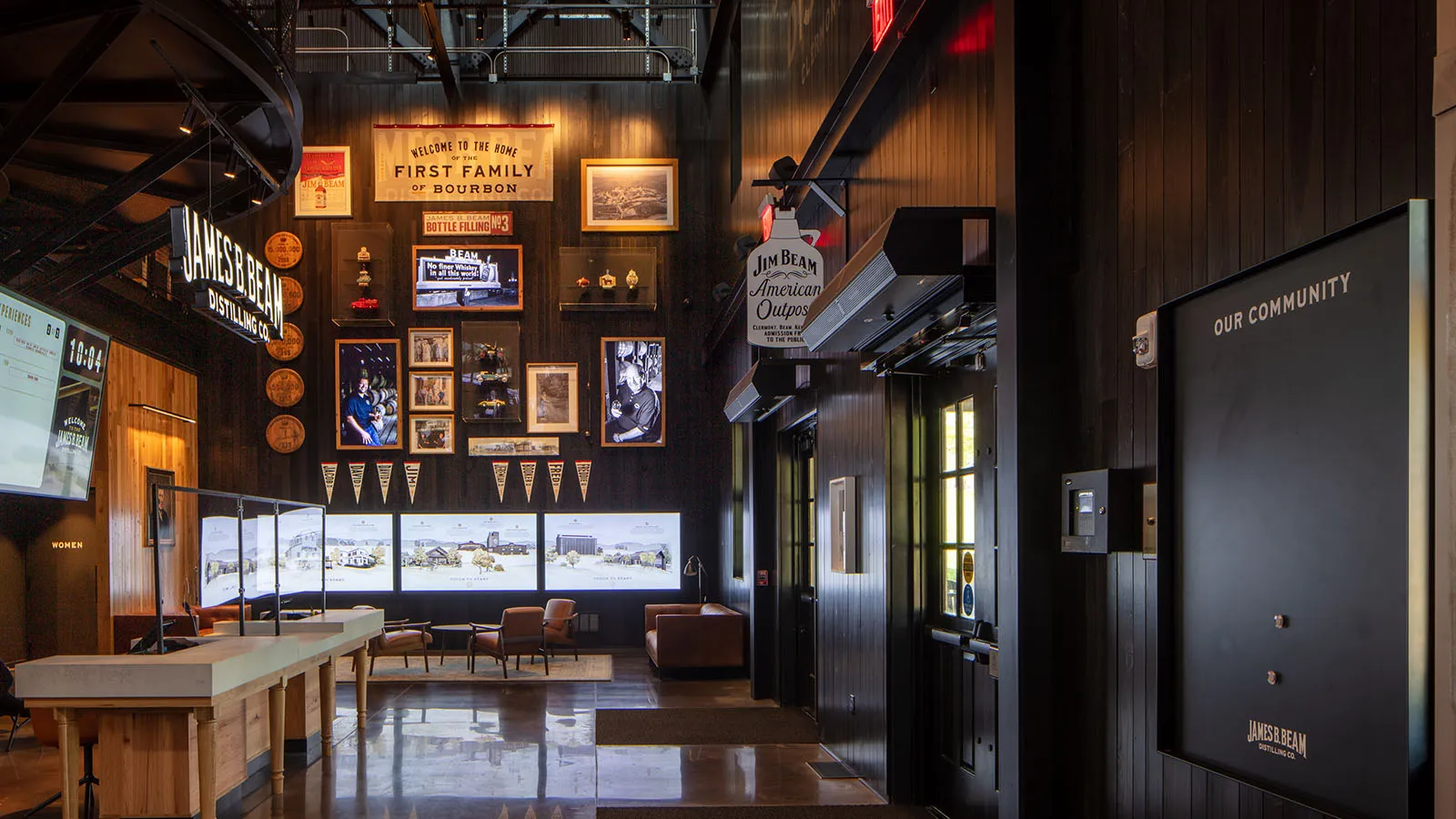 Front reception desk at the American Outpost distillery welcome center with a wall of screens. 