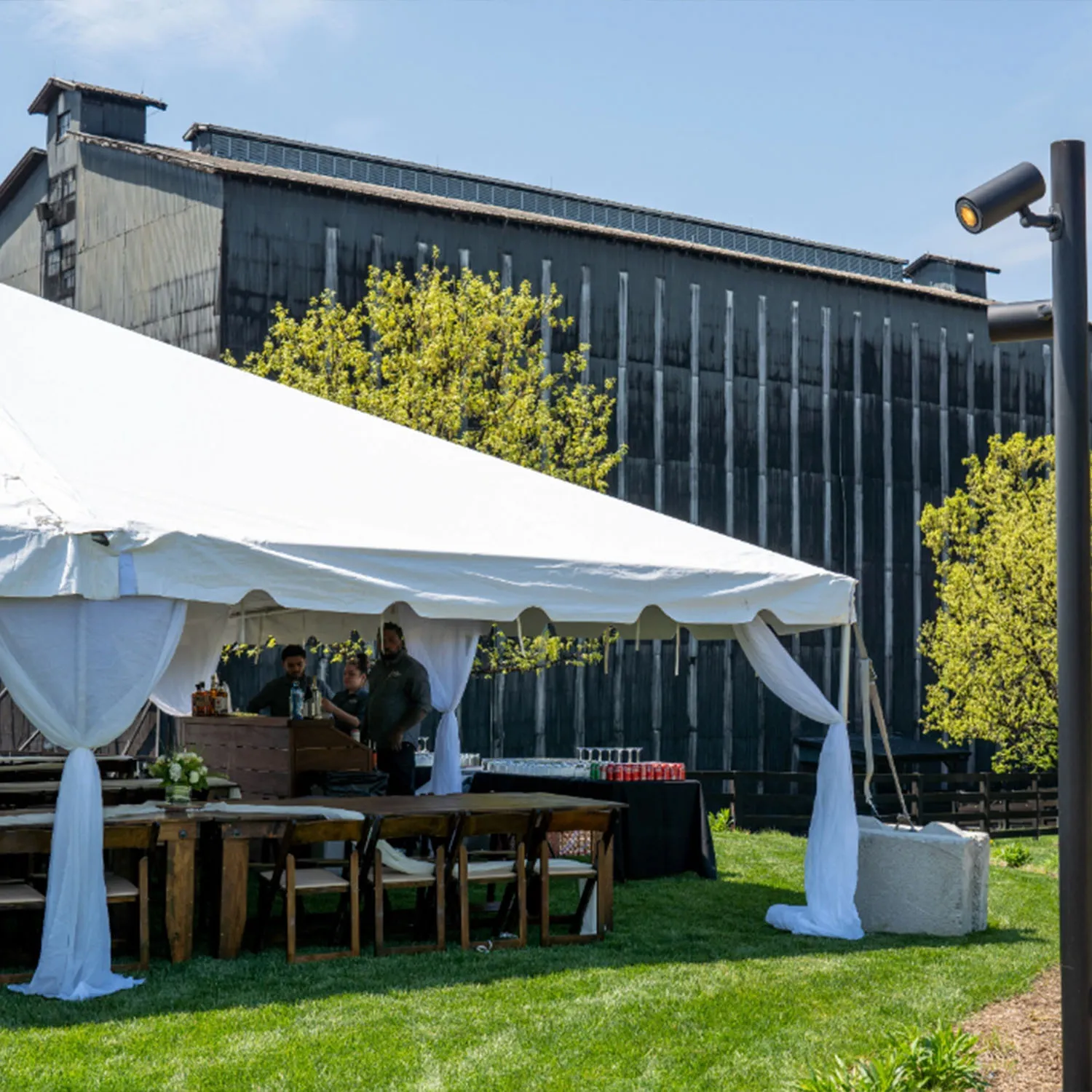 Event tent with an outdoor bar on the lawn, backed by a large warehouse at the Jim Beam distillery.