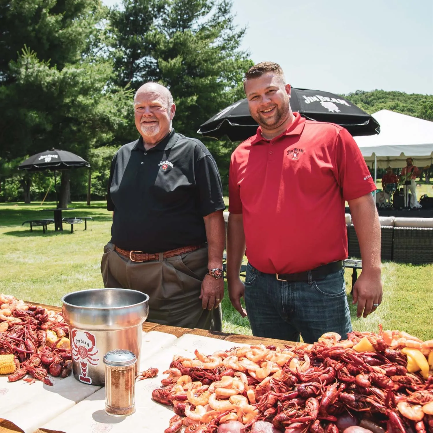 Fred Noe & Freddie Noe by a massive seafood boil at a Jim Beam outdoor event. 