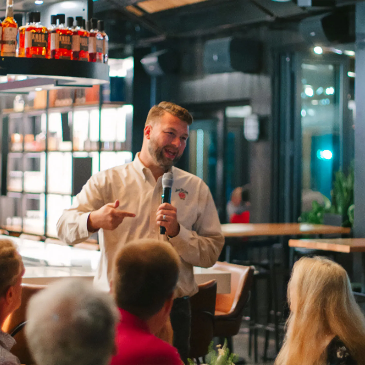 Freddie Noe, 8th generation distiller, speaking into a microphone at a dining event at The Kitchen Table.