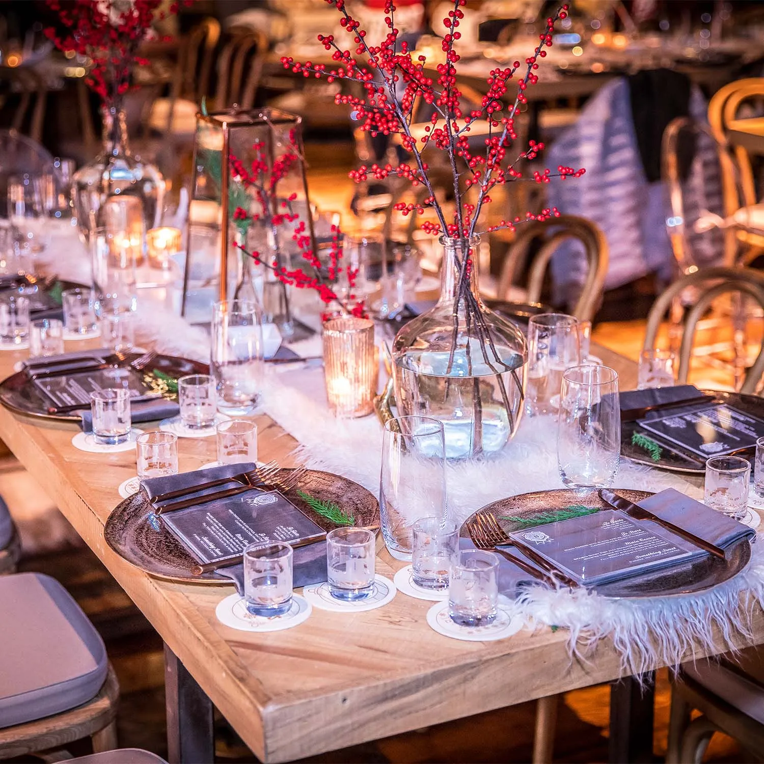 Elegant holiday dinner table setting with red berries and glassware for a Jim Beam Distilling Co. event.