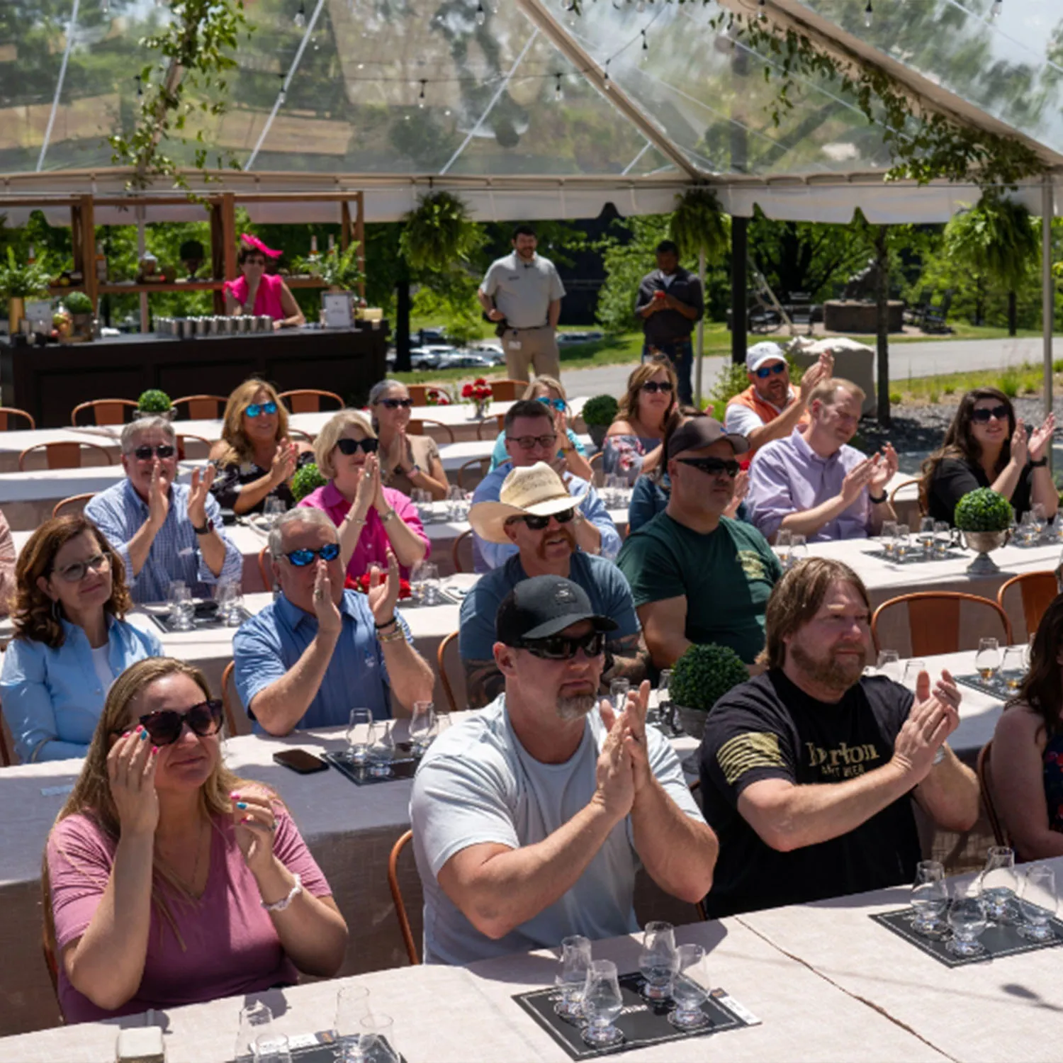 Guests clapping at an outdoor event held under a clear tent at James B. Beam Distilling Co.