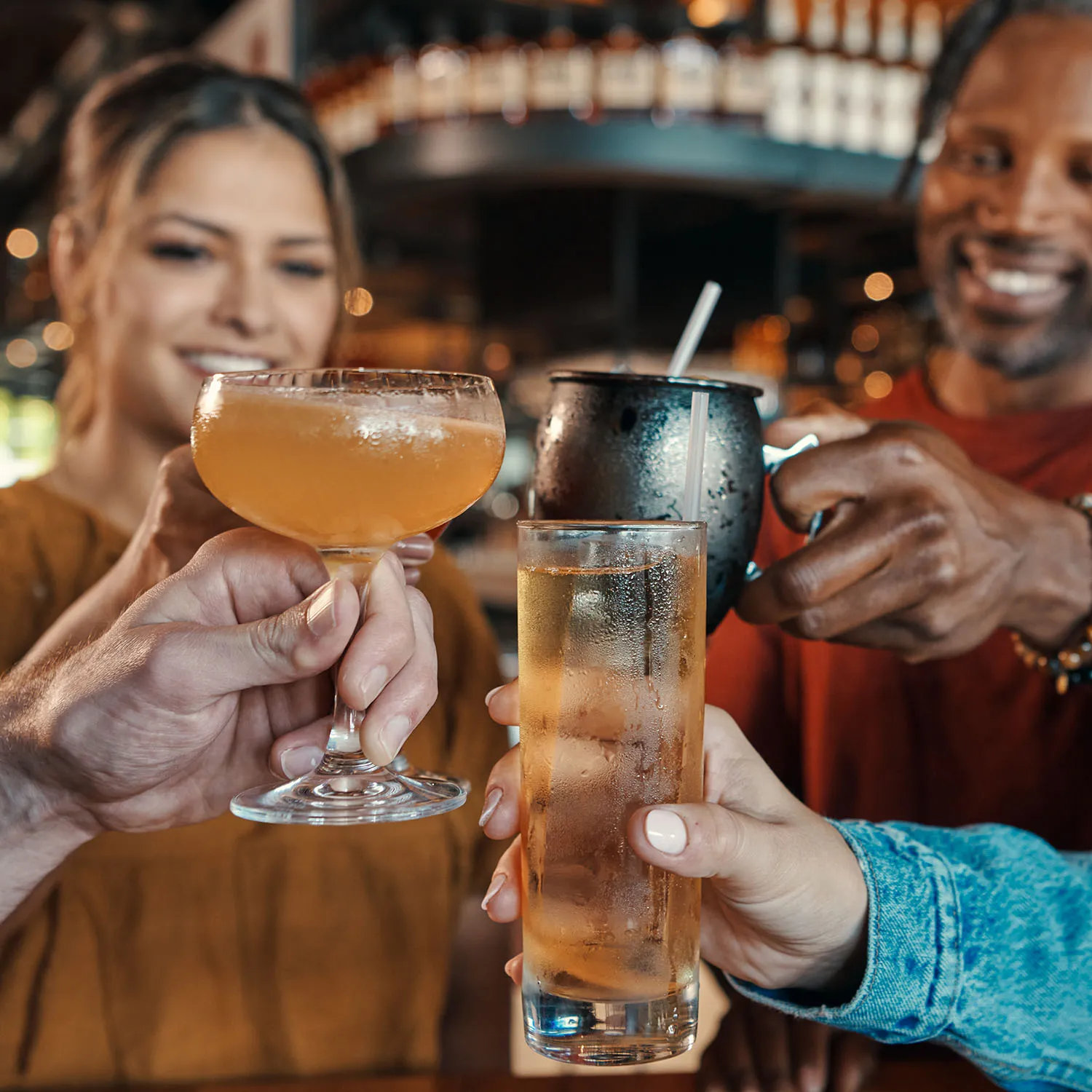 Close-up of people cheersing with various bourbon cocktails at The Kitchen Table bar.