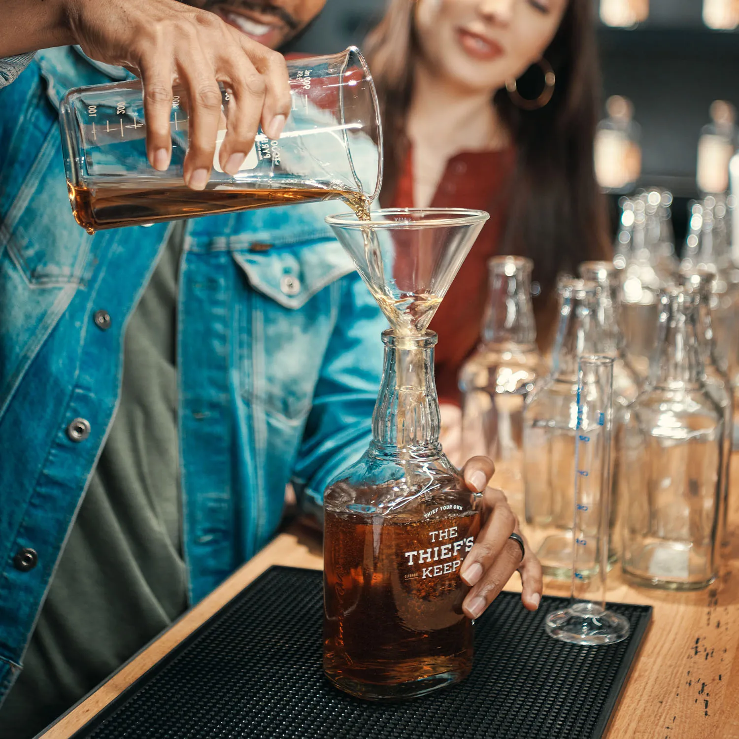 Visitor pouring bourbon from a beaker into a The Thief's Keep bottle at the distillery experience.