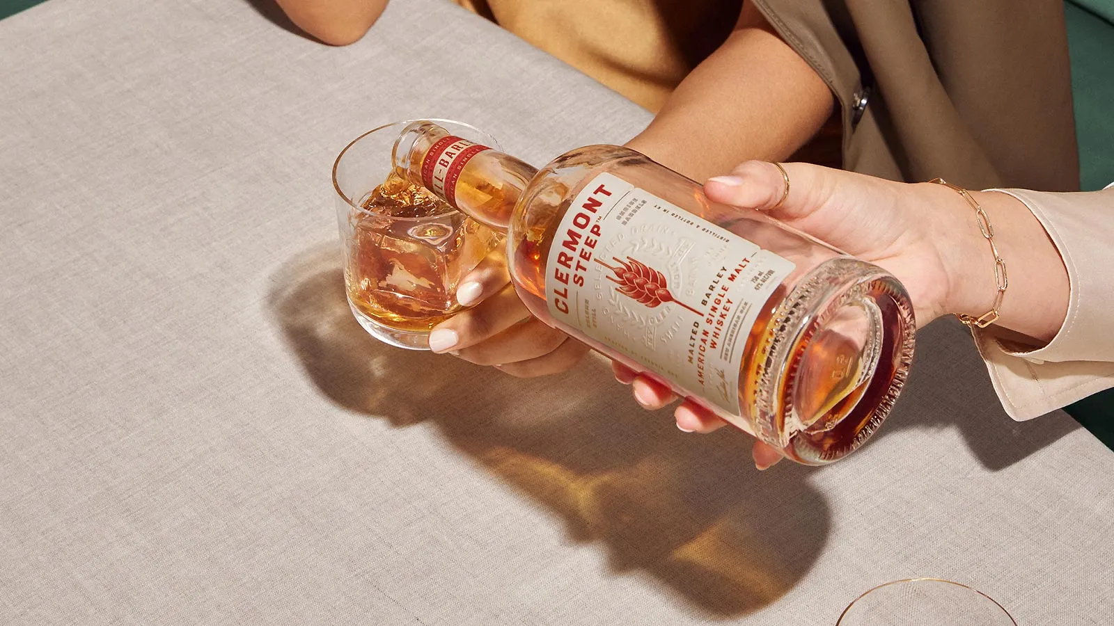 Serving drink on a glass from a bottle of Whisky Clermont Steep